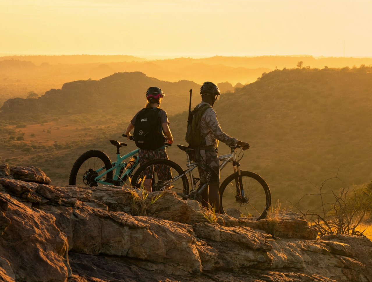 Two people watching the sunset with their mountain bikes