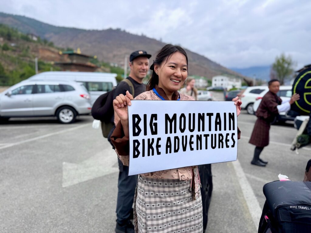 Bhutanese woman with welcome big mountain bike adventures sign