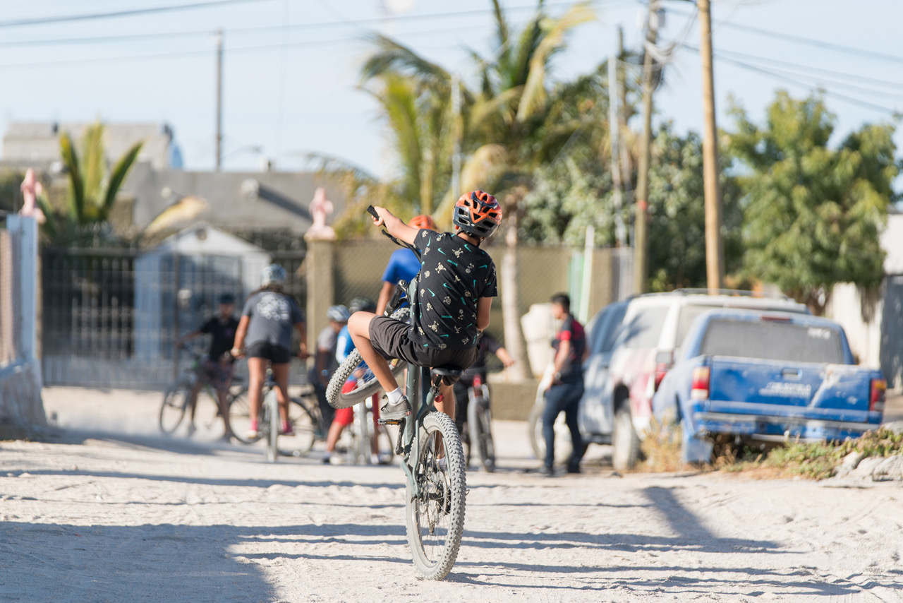 Youth doing a wheelie on a mountain bike in Mexico.